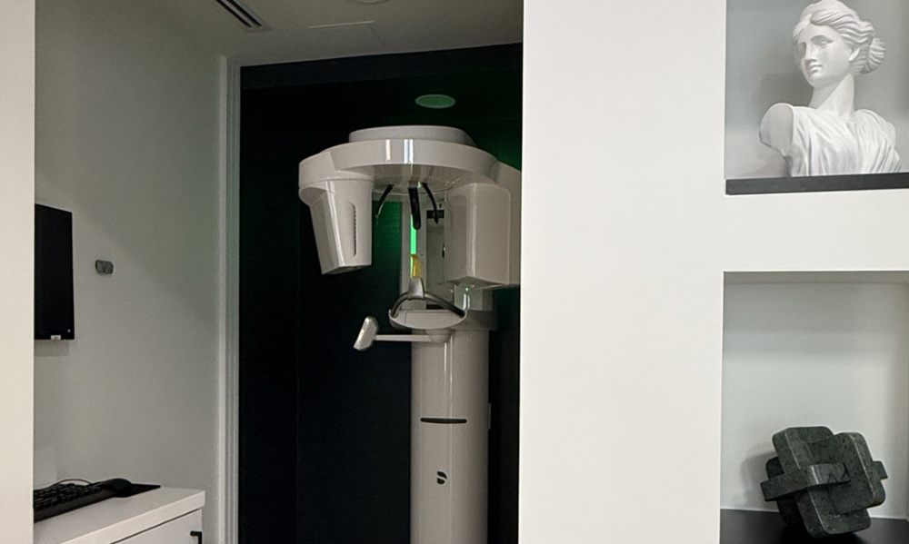 Modern dental panoramic X-ray machine in a sleek office with decorative sculpture on shelving